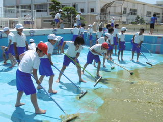 水を排水溝に押す子どもたち